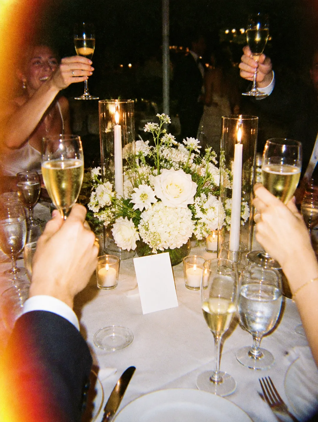 Guests raising their glasses at a candlelit table